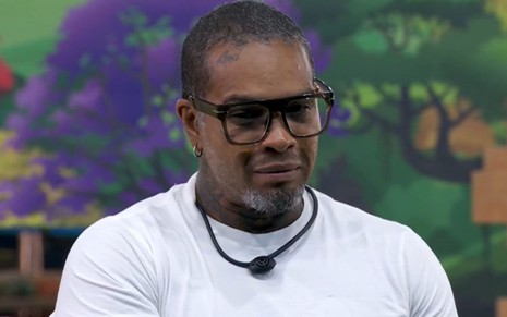 Rodriguinho usa camiseta branca e óculos de grau na área externa do BBB 24