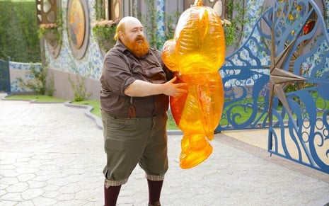 Phil Miler segura um balão em forma de urso em cena de A Caverna Encantada