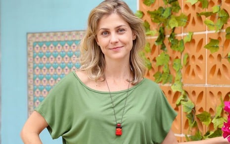 Christiana Ubach usa uma blusa verde e encara a câmera, dando um leve sorriso em ensaio de divulgação de A Infância de Romeu e Julieta