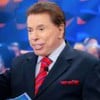 Silvio Santos está com uma mão estendida, no Programa Silvio Santos