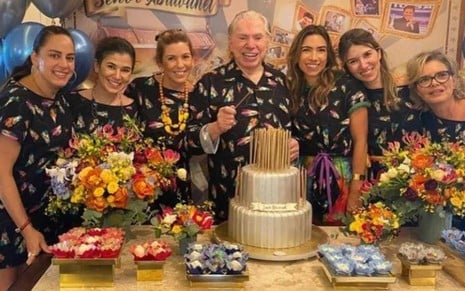 Silvio Santos com suas filhas em frente a mesa com bolo de aniversário. Da esquerda para a direita: Silvia, Rebeca, Daniela, Silvio, Patrícia, Renata e Cíntia