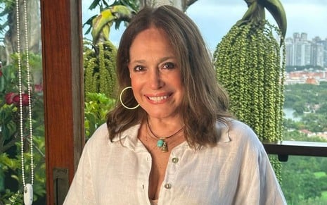 Susana Vieira usa uma blusa branca e encara a câmera, sorrindo