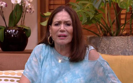 Susana Vieira em entrevista ao É de Casa, usando blusa azul e fazendo cara de confusa