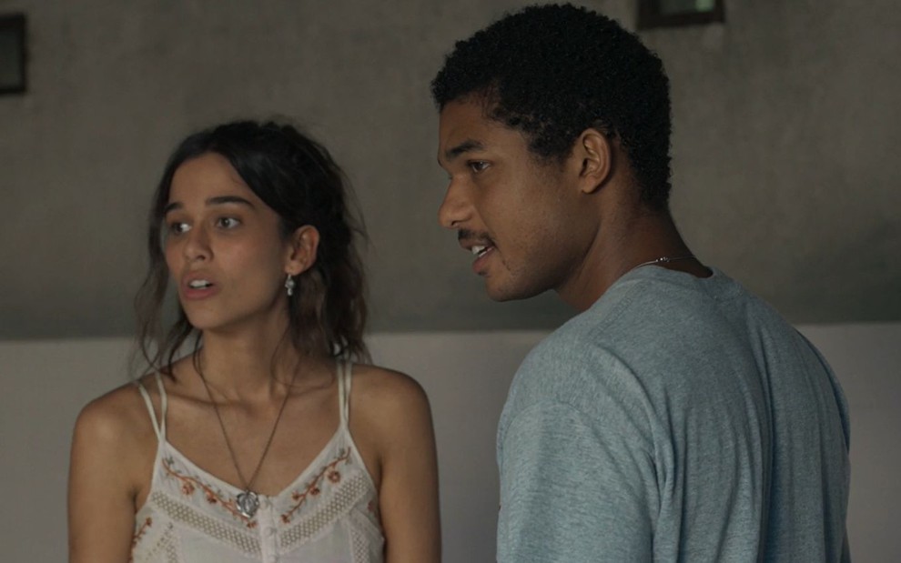 Mariana (Theresa Fonseca) e João Pedro (Juan Paiva) estão em pé e olham para o lado em cena da novela Renascer