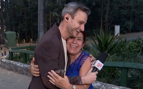 O repórter Tiago Scheuer abraça uma mulher em um parque durante link no Bom Dia São Paulo