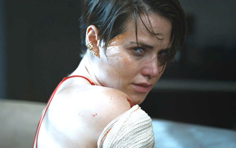 Letícia Colin com expressão séria em cena da novela Todas as Flores; ela está com um curativo no braço