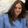 Vera Viel usa uma camisola hospitalar e sorri