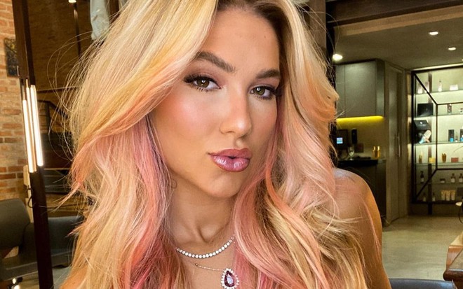 Virginia Fonseca tem os cabelos curtos e com mechas rosas; ela encara a câmera e faz bico