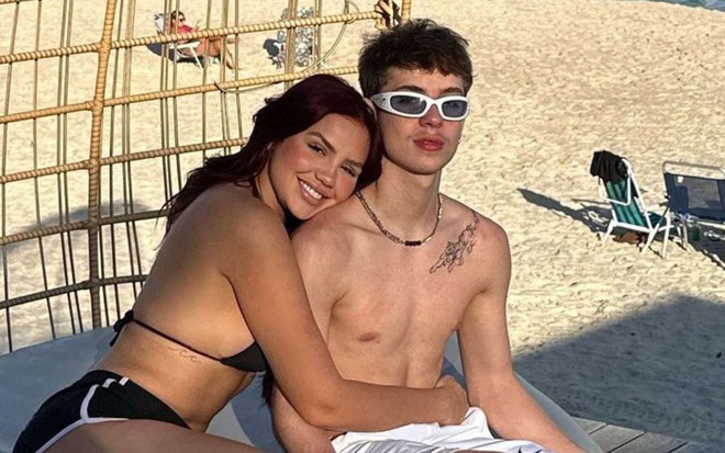 Vivi sorrindo e abraçando Juliano Floss na praia