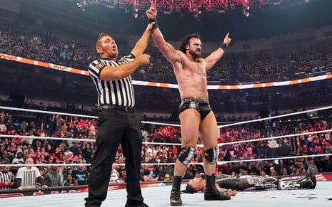 Juiz ergue os braços de Drew McIntyre em um ringue da WWE; Damian Priest está caído no chão