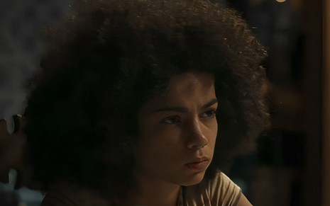Em cena de Renascer, Samantha Jones está com a expressão séria, olhando para alguém