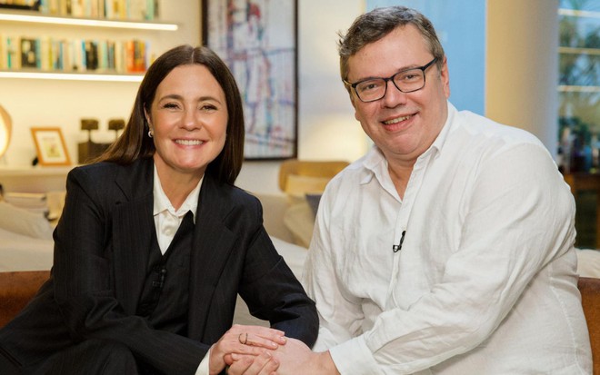 Adriana Esteves e João Emanuel Carneiro em entrevista ao Fantástico para divulgar a novela Mania de Você; ela veste paletó preto e ele, camisa branca