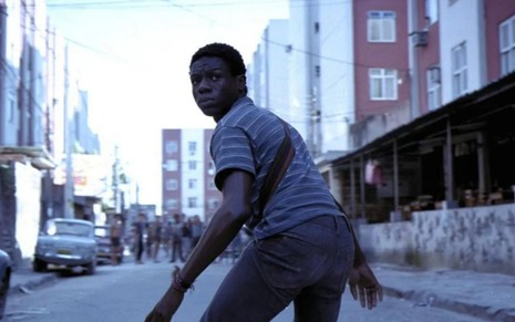 Alexandre Rodrigues em Cidade de Deus (2002), com um fuzil na mão, olhando para trás com expressão de medo