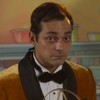 De terno, Eduardo Sterblitch fala em microfone antigo em cena da novela Garota do Momento