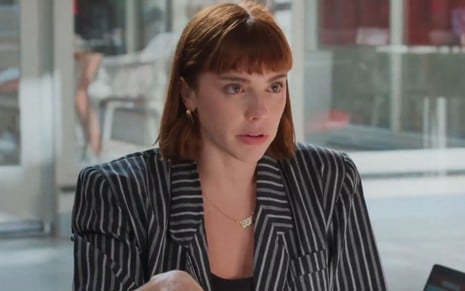 Solange (Alice Wegmann) na Tomorrow, usando um blazer preto com listas brancas, e feição séria