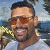 Amaury Lorenzo sorri e usa um óculos com lentes laranjas