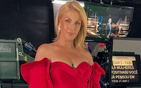 Ana Hickmann de vestido vermelho, em frente a camêras e equipamentos de vídeo da Record