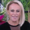 Ana Maria Braga sorridente no cenário Mais Você, sentada à mesa, e usando blusa preta de veludo com transparência