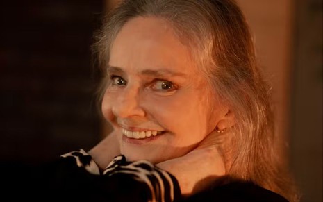 Angela Ro Ro está sorridente, com as duas mãos apoiadas na nuca