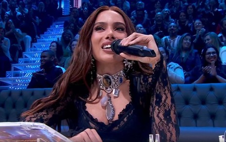 A cantora Anitta com microfone na mão, no júri da Dança dos Famosos no Domingão com Huck