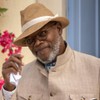 Samuel L. Jackson faz um aceno de cabeça com a mão em um chapéu, para uma mulher ruiva que está de costas para a câmera