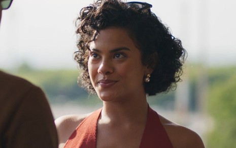 Bella Campos sorri em cena como Maria de Fátima na novela Vale Tudo