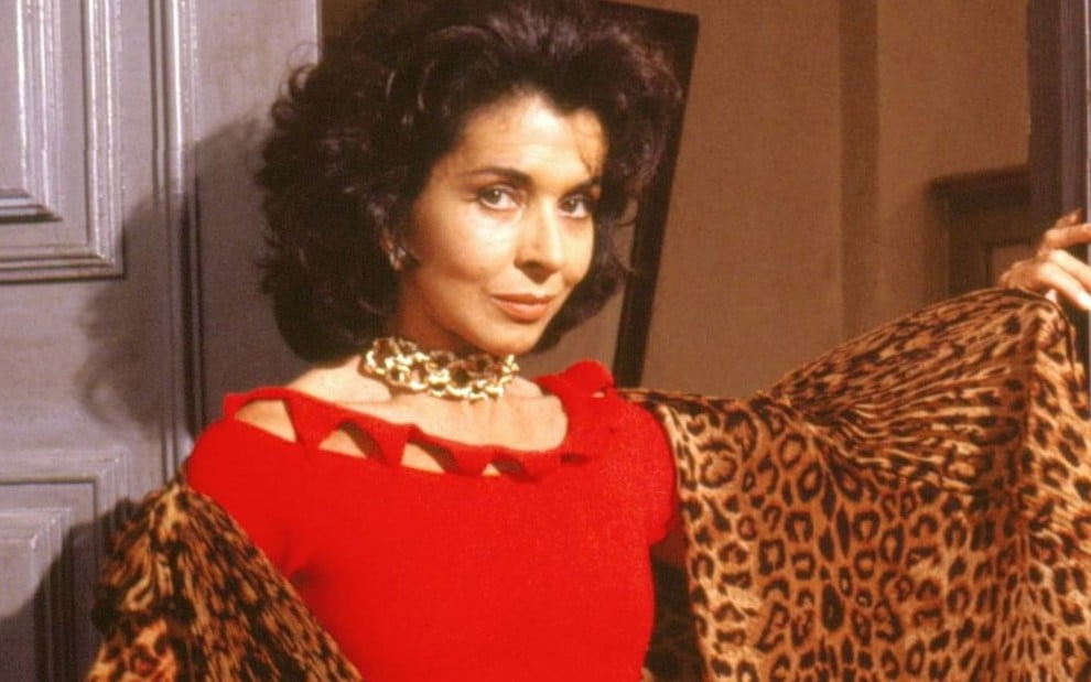 A atriz Betty Faria de blusa vermelha, expressão séria, caracterizada como Tieta na novela Tieta (1989)