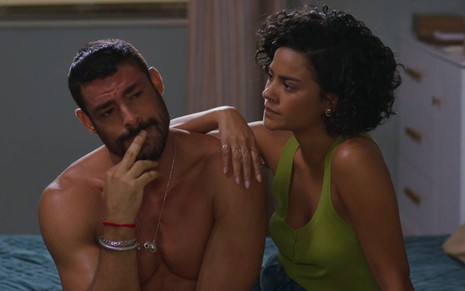 Cauã Reymond e Bella Campos sentados lado a lado em cena da novela Vale Tudo