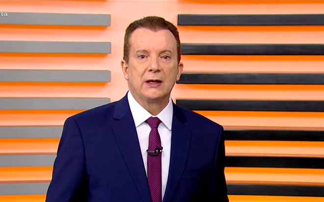 O apresentador Celso Russomanno no palco do Cidade Alerta com um terno preto, blusa branca e gravata vinho