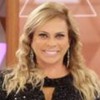 Christina Rocha posando em frente a um telão com o logo do Casos de Família; ela aparece sorridente, com vestido preto de lantejoulas, e segura ficha do programa nas mãos