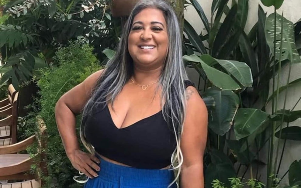 Cida Santos, campeã do BBB 4, com a mão na cintura e sorrindo para foto