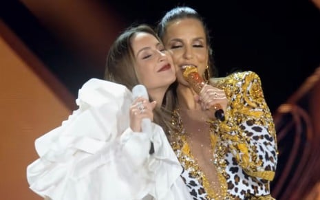 Claudia Leitte e Ivete Sangalo com os rostos colados enquanto cantam