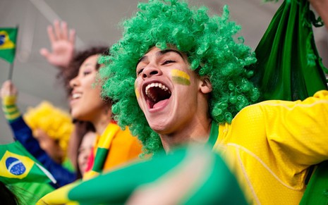 Torcedores do Brasil vibram com camisas amarelas, perucas verdes e bandeira em clima de Copa do Mundo