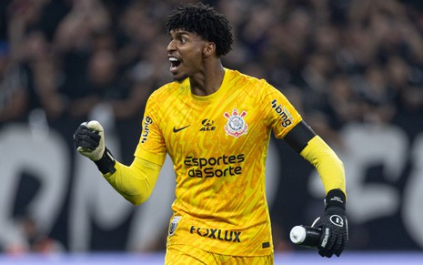 O goleiro Hugo Souza usa uniforme amarelo e faz gesto de comemoração em jogo do Corinthians ao vivo