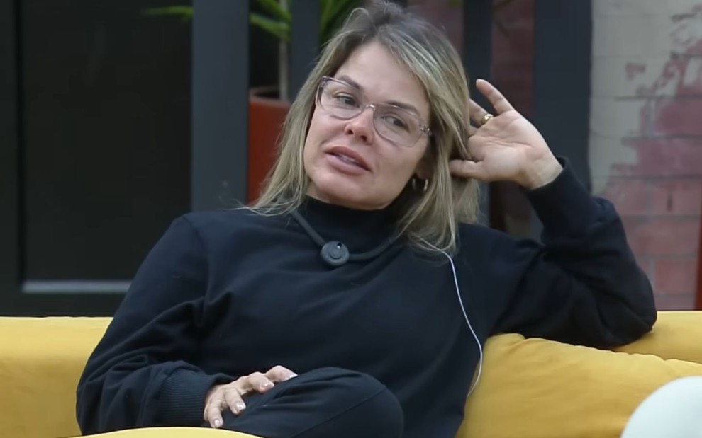Cristianne Moliterno sentada em sofá no Power Couple Brasil
