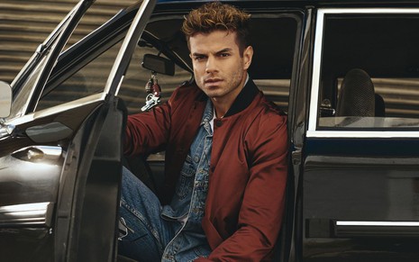 Daniel Blanco em DNA do Crime, posando com jaqueta vinho dentro de um carro