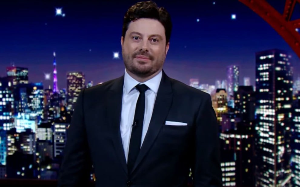 Danilo Gentili de terno e gravata, no cenário do The Noite