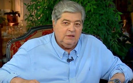 Datena em entrevista ao Sensacional; ele aparece sentado em uma cadeira, usando camisa azul-claro