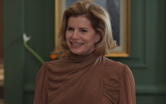 Debora Bloch sorri em cena como Odete na novela Vale Tudo