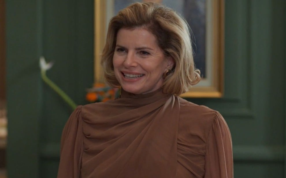 Debora Bloch sorri em cena como Odete na novela Vale Tudo