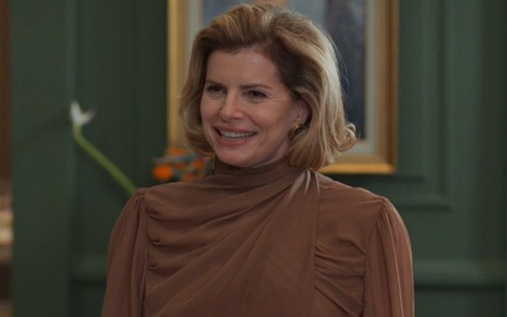 Debora Bloch sorri em cena como Odete na novela Vale Tudo