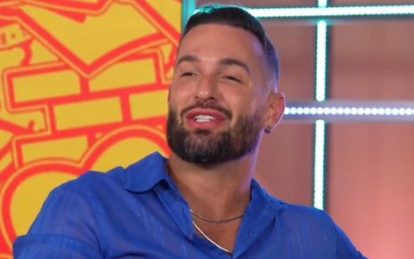 Diego Hypolito usa uma camisa azul e está falando na chamada do BBB 25