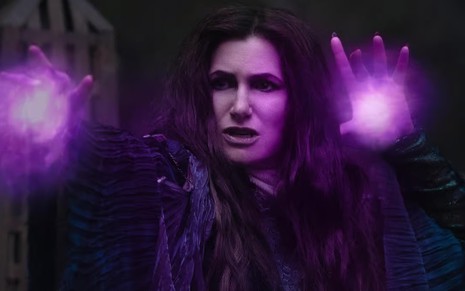 Kathryn Hahn está em posição de ataque, com feitiços roxos saindo de suas mãos