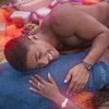 Os atores Humbeto Morais e Clara Moneke deitados, sorrindo, ele com a mão na barriga dela em cena de Dona de Mim