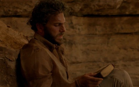 Paulo (Elam Lima) está sujo dentro de uma caverva em cena da novela A Caverna Encantada