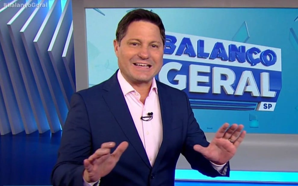 Eleandro Passaia usa terno e gesticula; ao fundo está o logo do Balanço Geral SP no telão