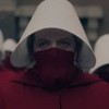 Elisabeth Moss usa uma roupa vermelha com chapéu branco; só é possível ver os olhos da atriz na veste típica das aias em The Handmaid's Tale