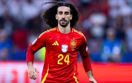 Cucurella, da Espanha, veste uniforme vermelho com detalhes amarelos durante jogo da seleção