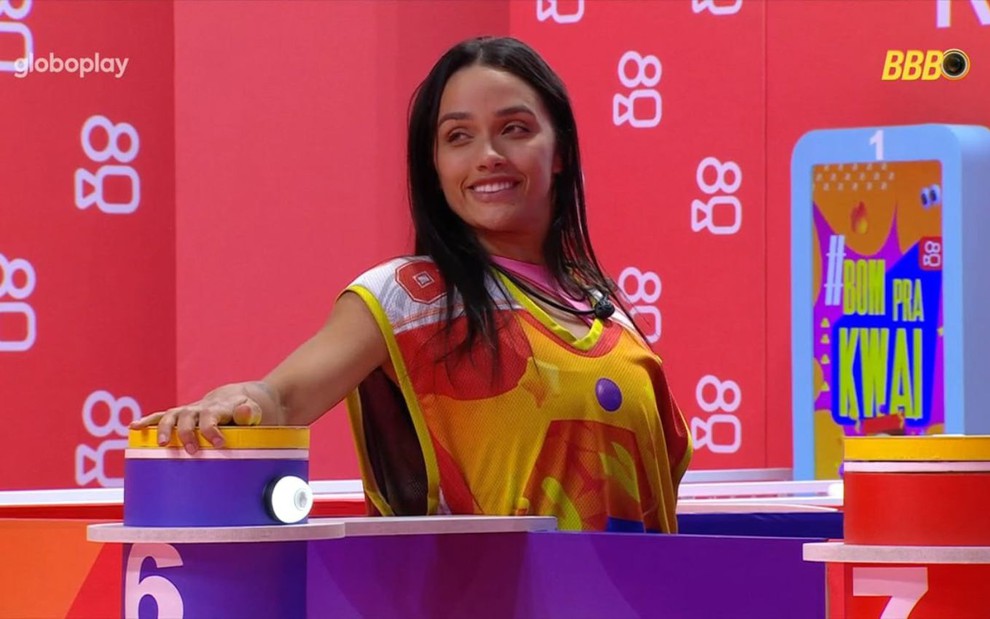 Eva Pacheco sorrindo e segurando o botão na Prova do Líder do BBB 25