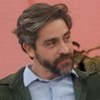 Felipe Abib sentado no sofá do Encontro, usando casaco verde-escuro e camisa azul-claro